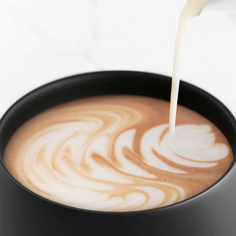 Milk is poured into a black Ember Mug.