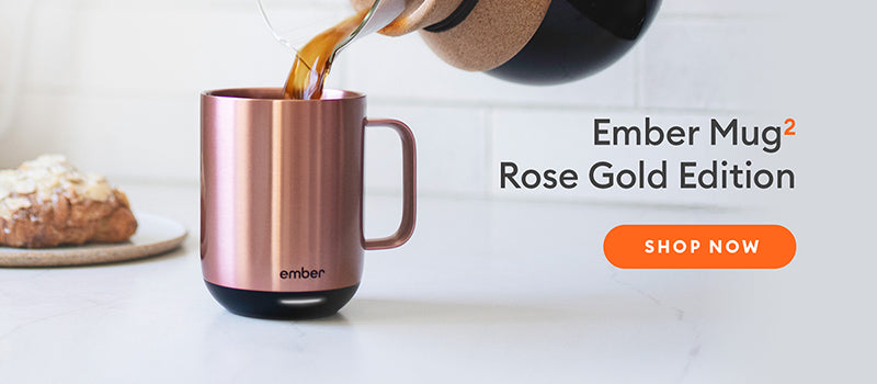 Coffee being poured into an Ember Mug² in Rose gold with a baked good in the background.