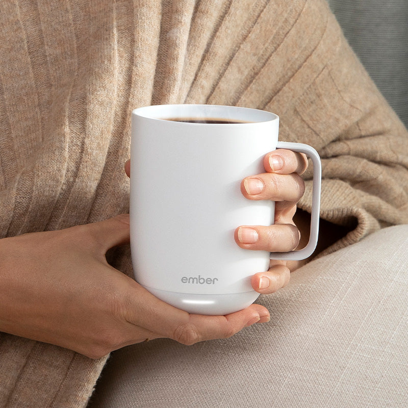 A woman gently holds a white Ember Mug